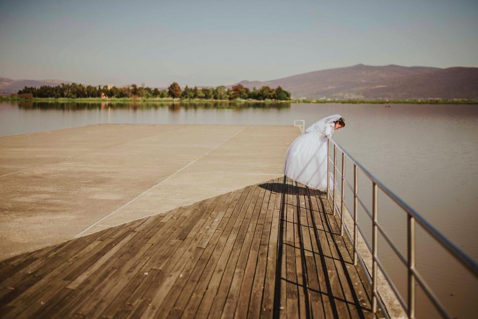 Free Image of Bride on a pier gazing at water 