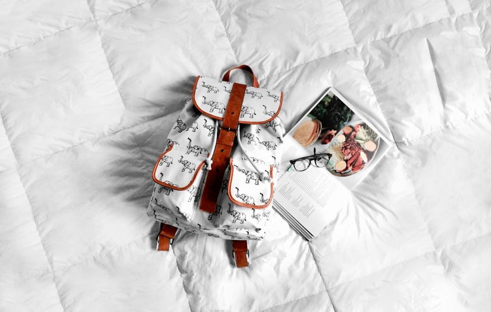 Free Image of Backpack and book on a cozy bed 