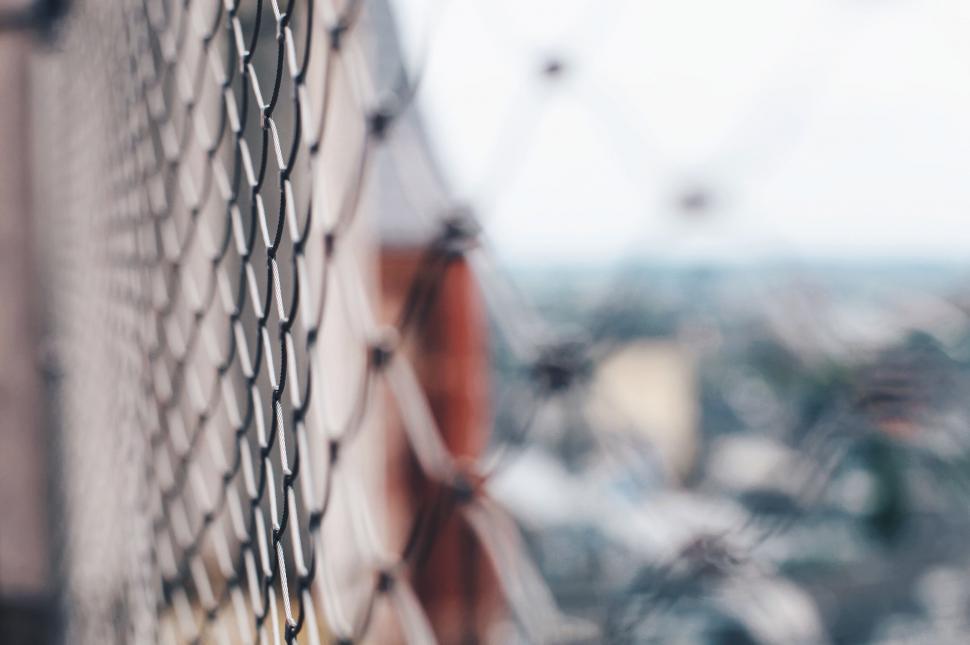 Free Image of Focused fence with blurry city background 