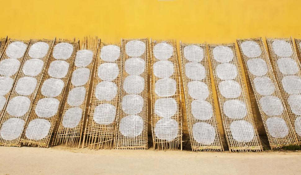 Free Image of Bamboo circular mats against a yellow wall 