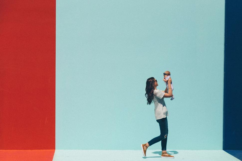 Free Image of Mother playing with baby against colorful walls 