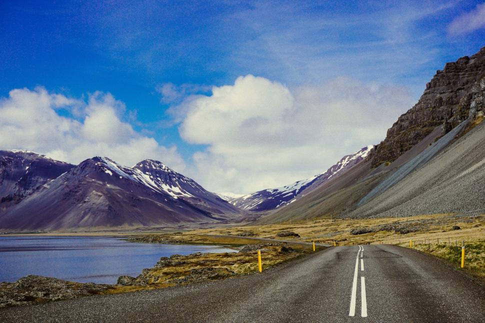 Free Image of Open road amidst snowy mountains and lake 