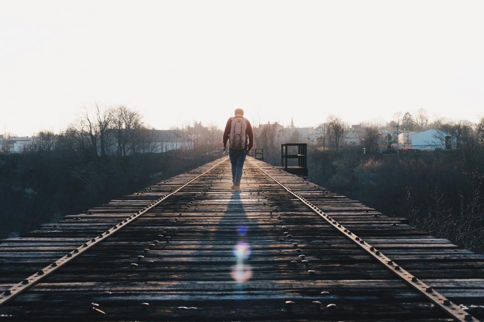 Free Image of Man walking on railroad tracks at sunset 