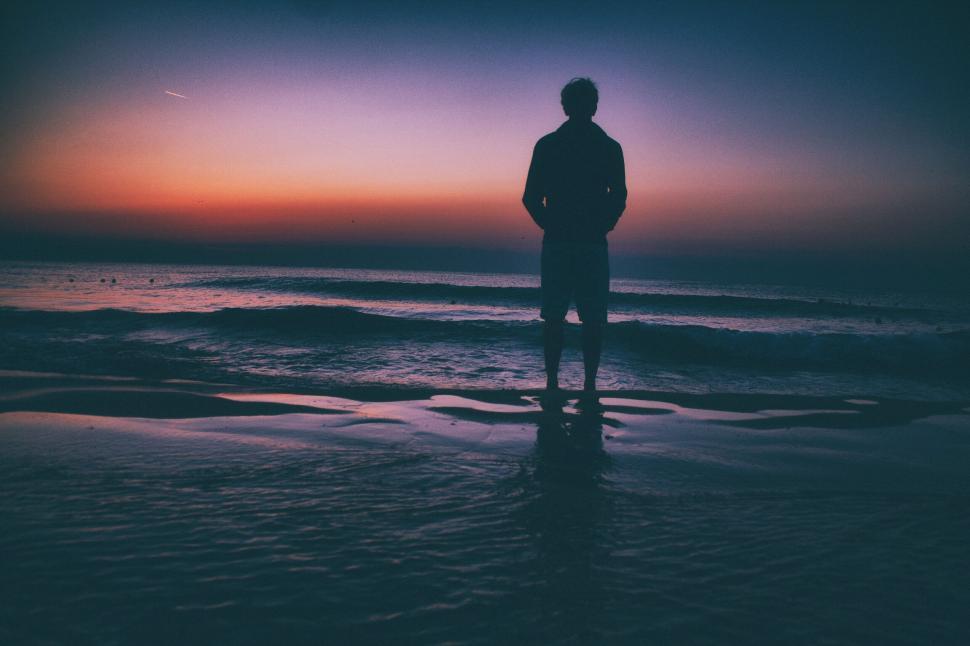 Free Image of Silhouetted man standing on the beach 