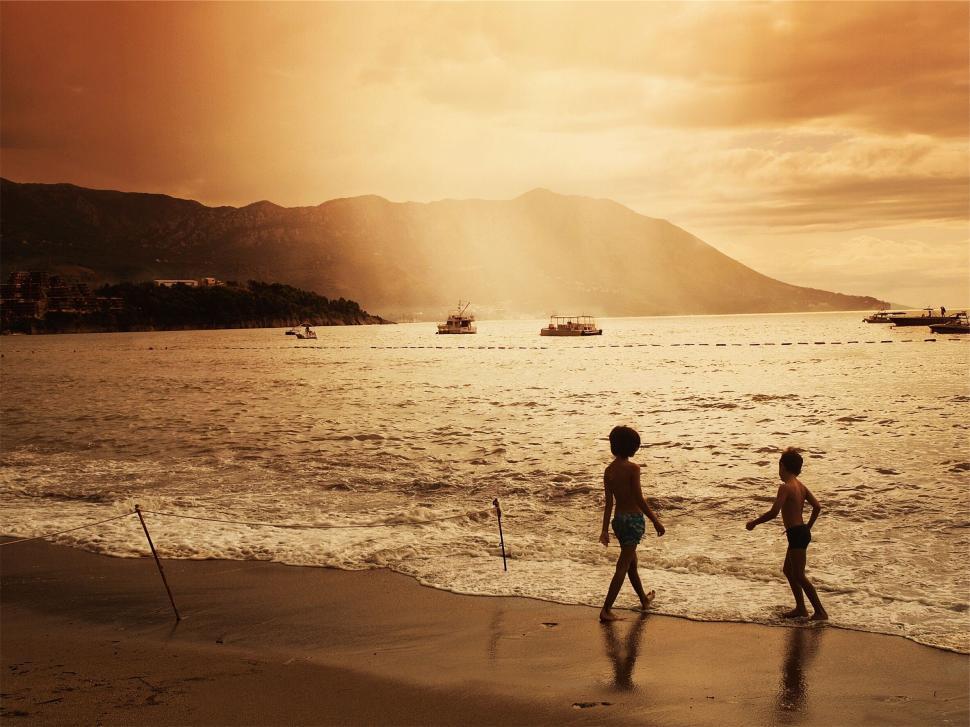 Free Image of Children playing on a beach at sunset 