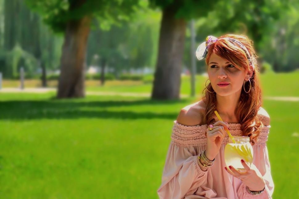 Free Image of Woman holding a drink in a park 