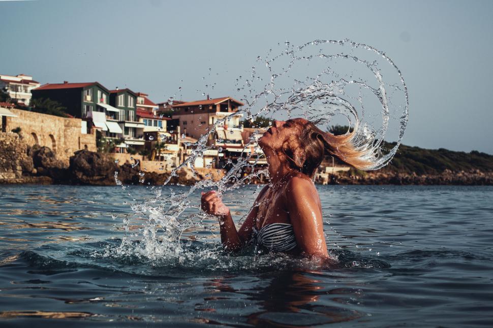 Free Image of Woman splashing water in sea at sunset 