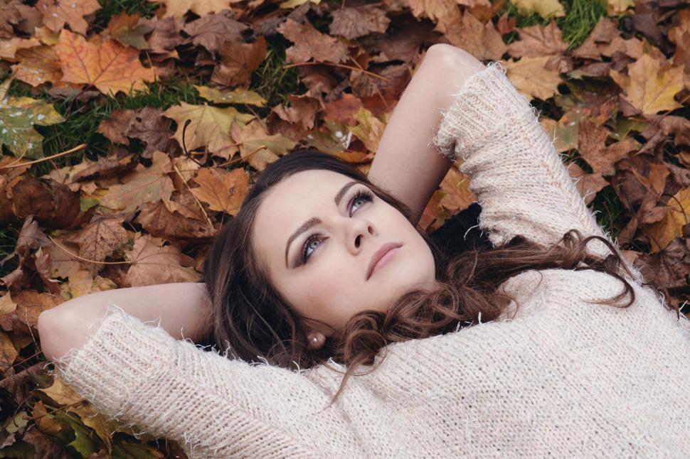 Free Image of Woman lying in autumn leaves with face blurred 