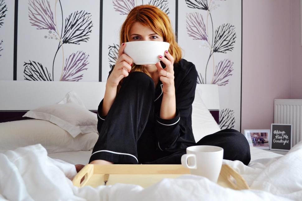 Free Image of Woman in bed covering face with a book 