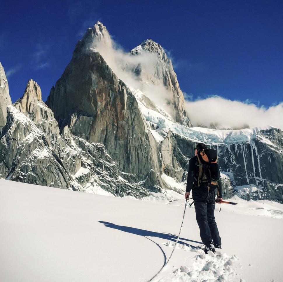 Free Image of Explorer in snow with towering mountains 