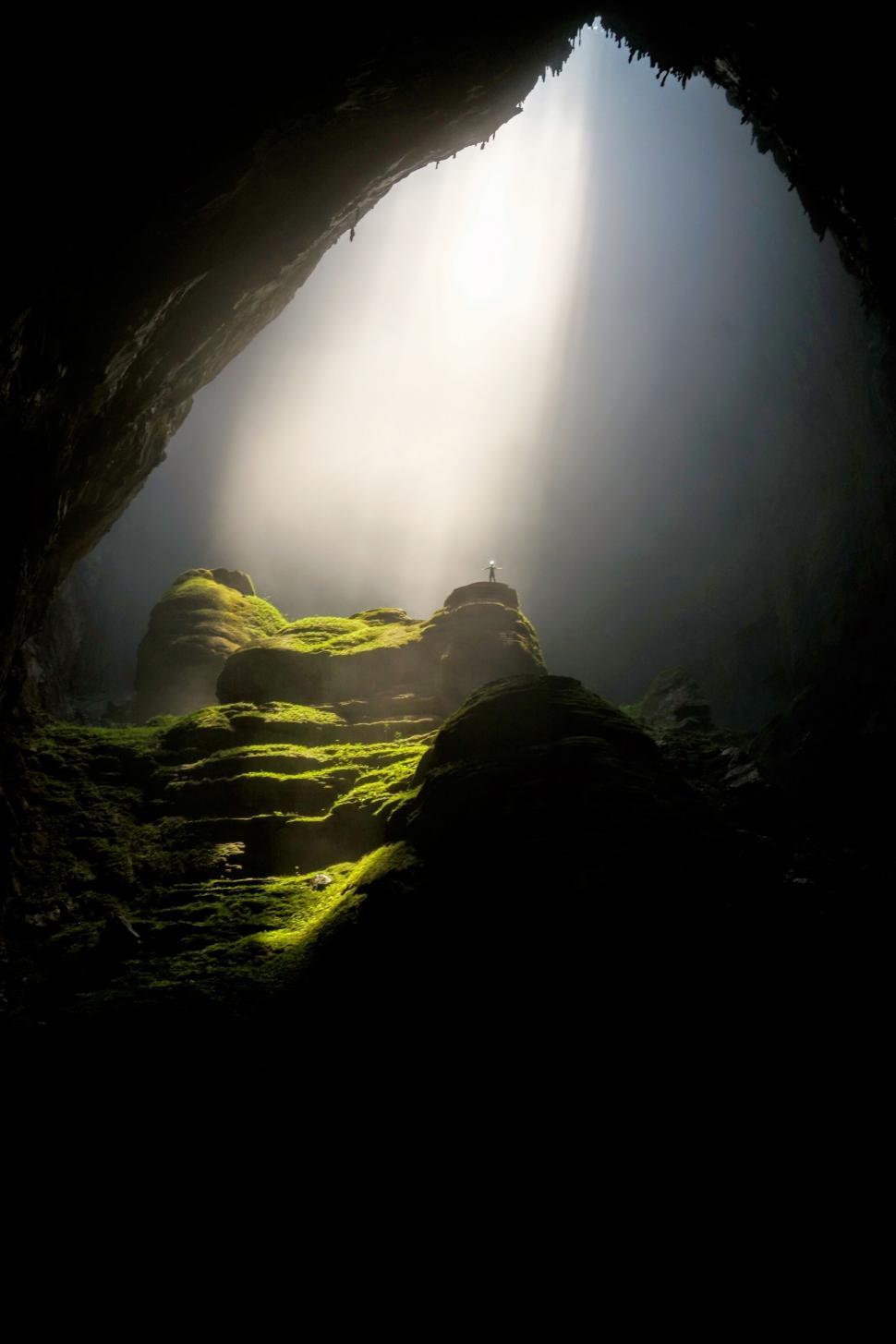 Free Image of Cave entrance with light and lone figure 