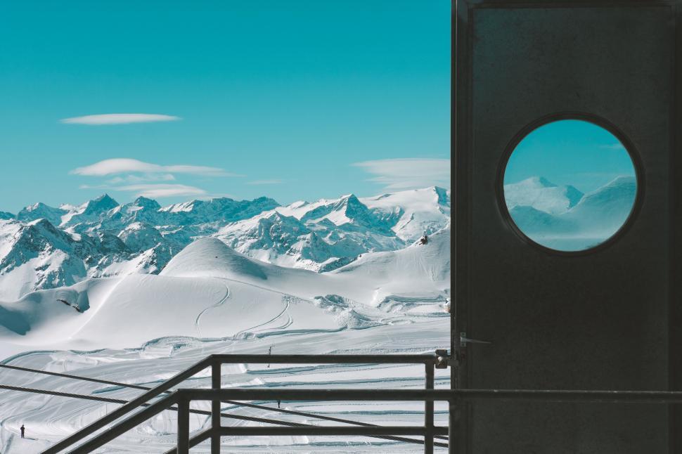Free Image of Snowy mountains viewed through a circular window 