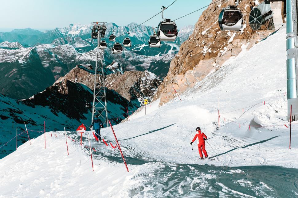 Free Image of Vibrant skier descending a mountain slope with cable cars 