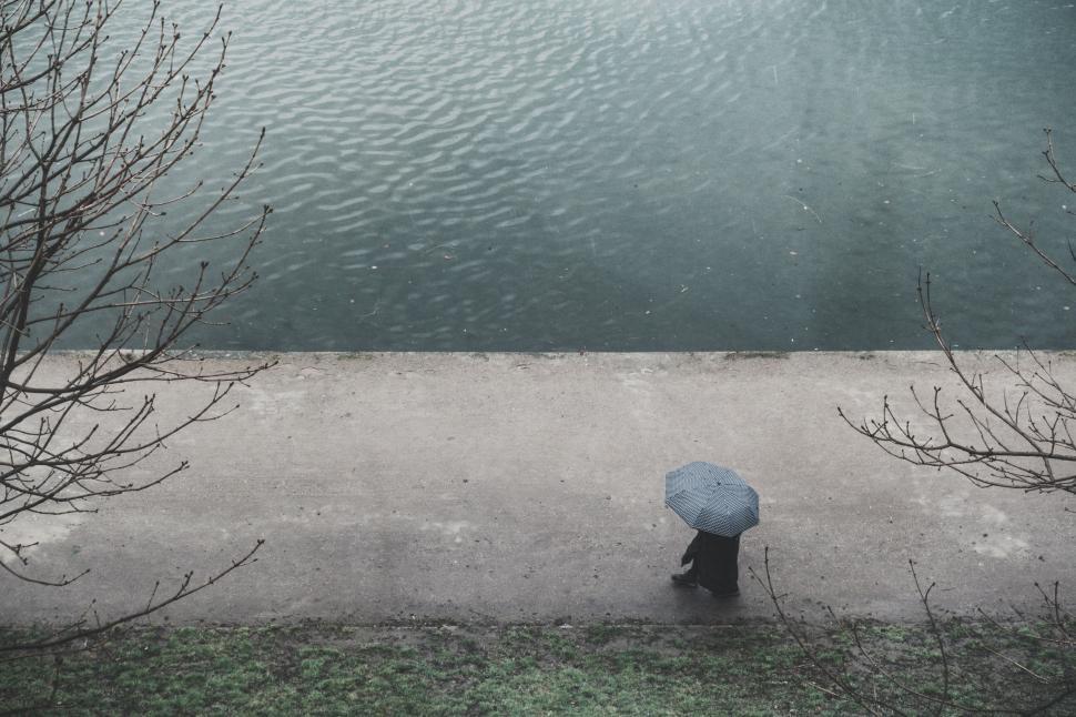 Free Image of Solitary figure with umbrella by the water s edge 