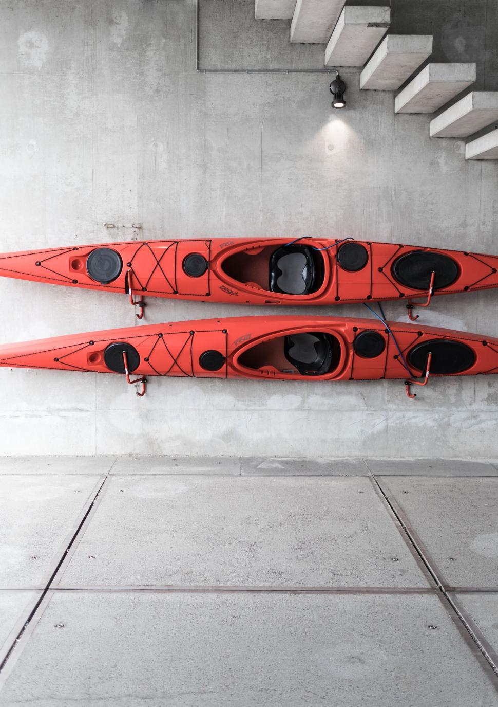 Free Image of Red kayaks stored on a concrete wall 