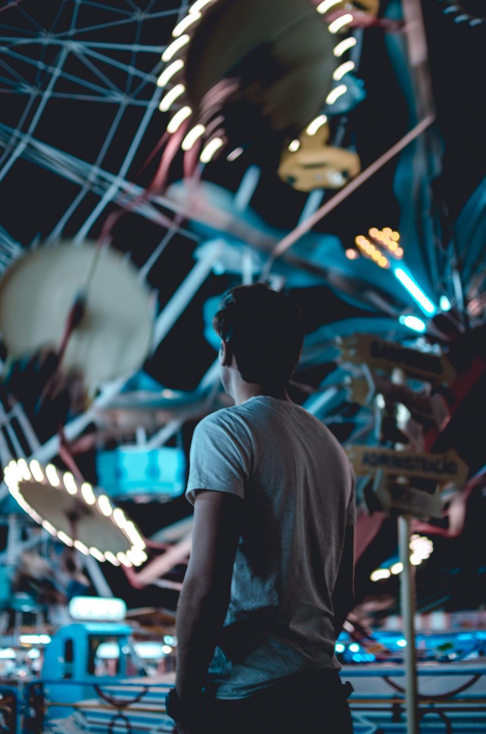 Free Image of Man gazing at amusement park rides at night 