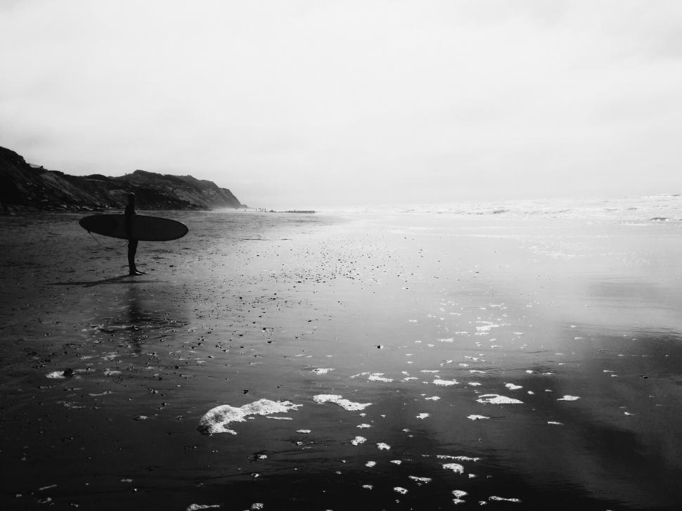 Free Image of Surfer with board on moody beachscape 