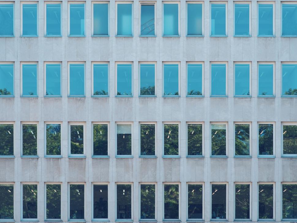 Free Image of Repetitive pattern of building windows reflecting sky 