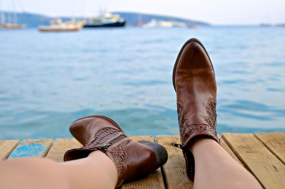 Free Image of Relaxing feet with a seaside view and boats in the background 