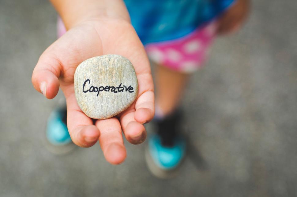 Free Image of Child holding a stone with text cooperative 