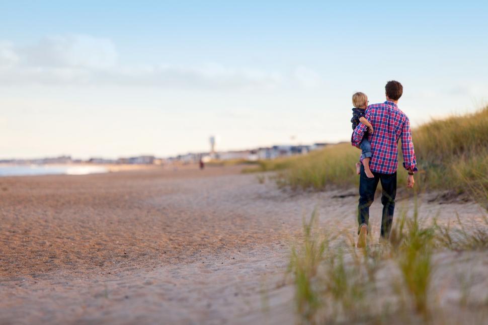 Free Image of Father carrying son on beach walk 