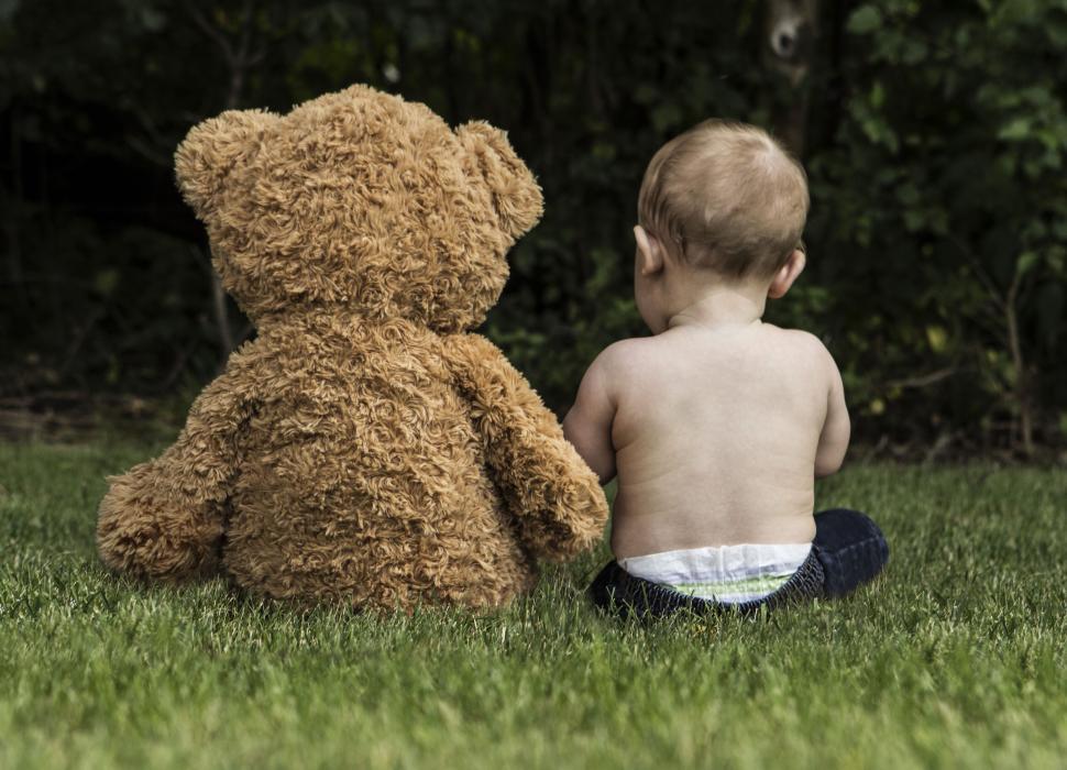 Free Image of Teddy bear sitting with a baby on grass 