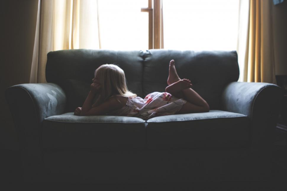 Free Image of Child relaxing on a couch in dim room 