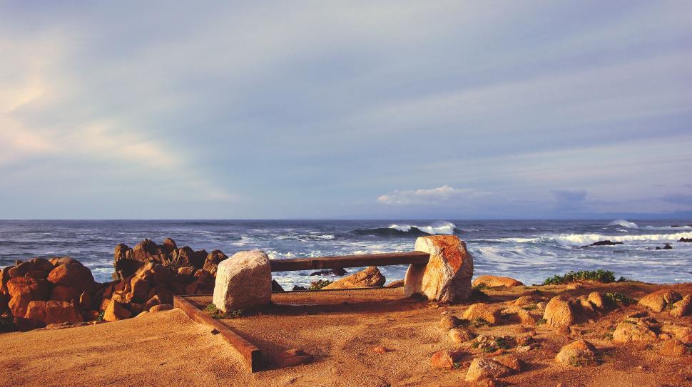 Free Image of Serene seascape with rustic bench and rocks 