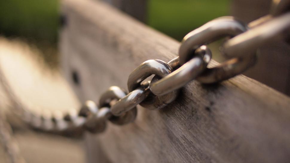 Free Image of Metal chain links on a wooden post close-up 