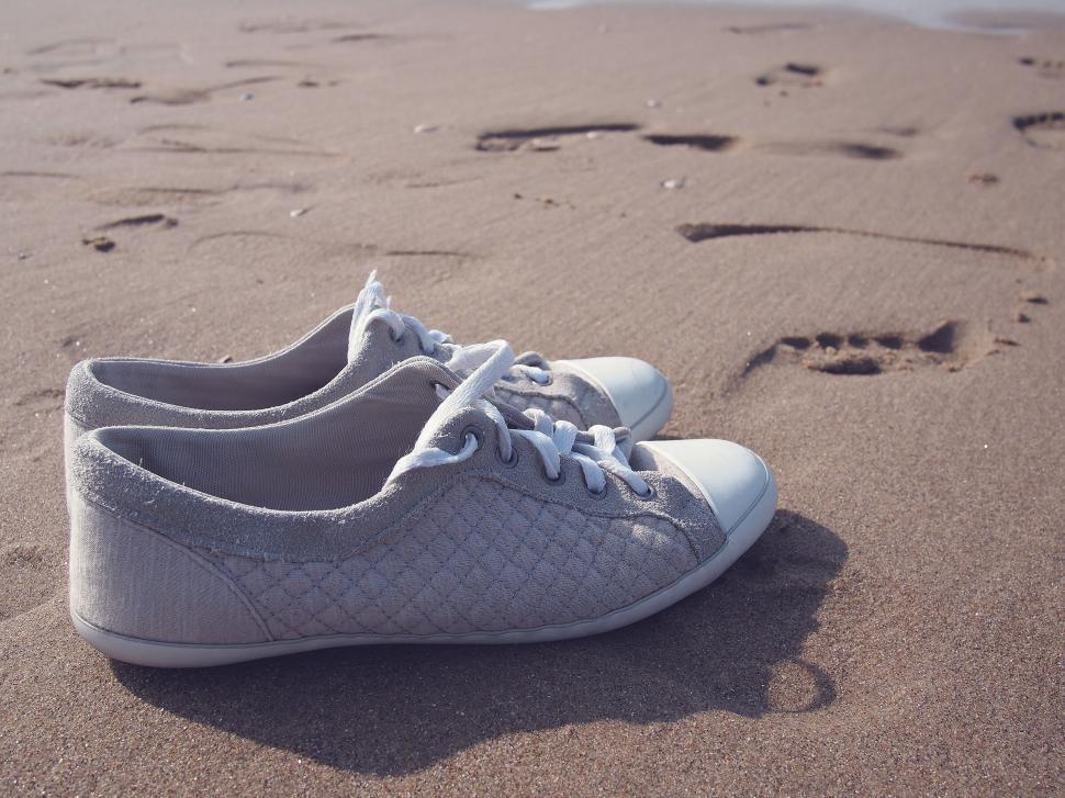 Free Image of Pair of sneakers on a sandy beach 