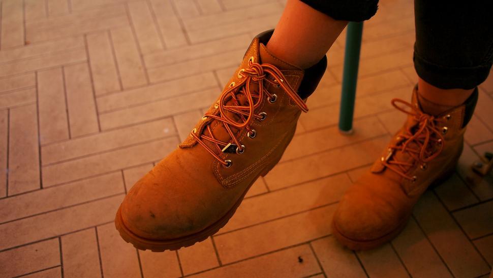 Free Image of Close-up of worn orange boots on a floor 