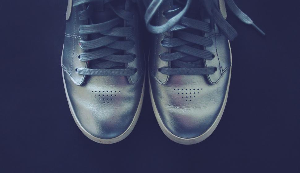 Free Image of Metallic silver shoes with laces on dark background 
