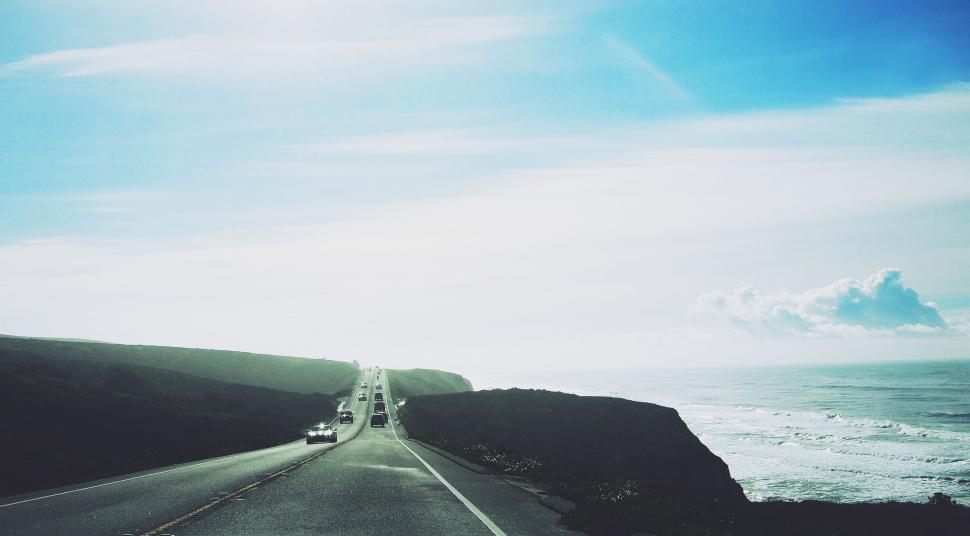 Free Image of Coastal road by the sea under clear blue sky 