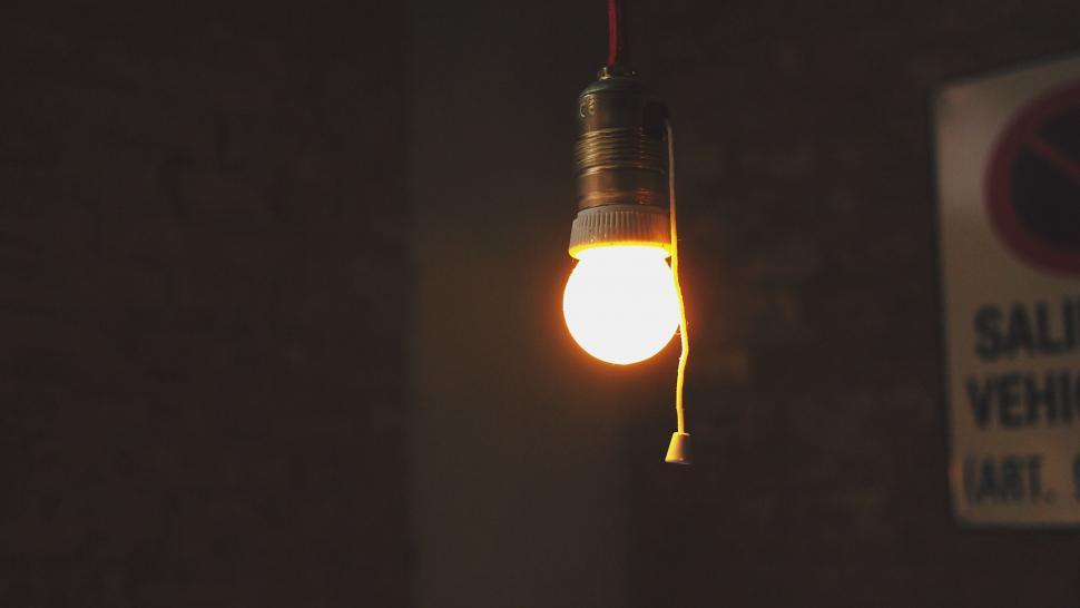 Free Image of Single lit bulb in a dim room 