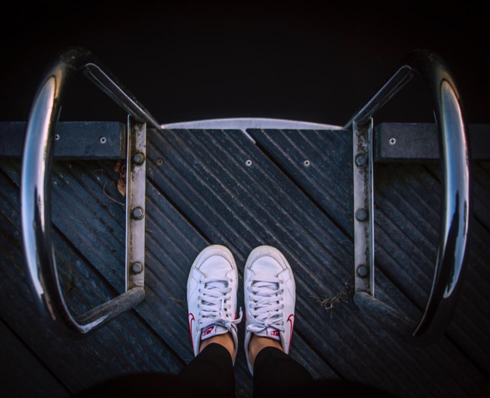 Free Image of Looking down on feet and steel ladder steps 