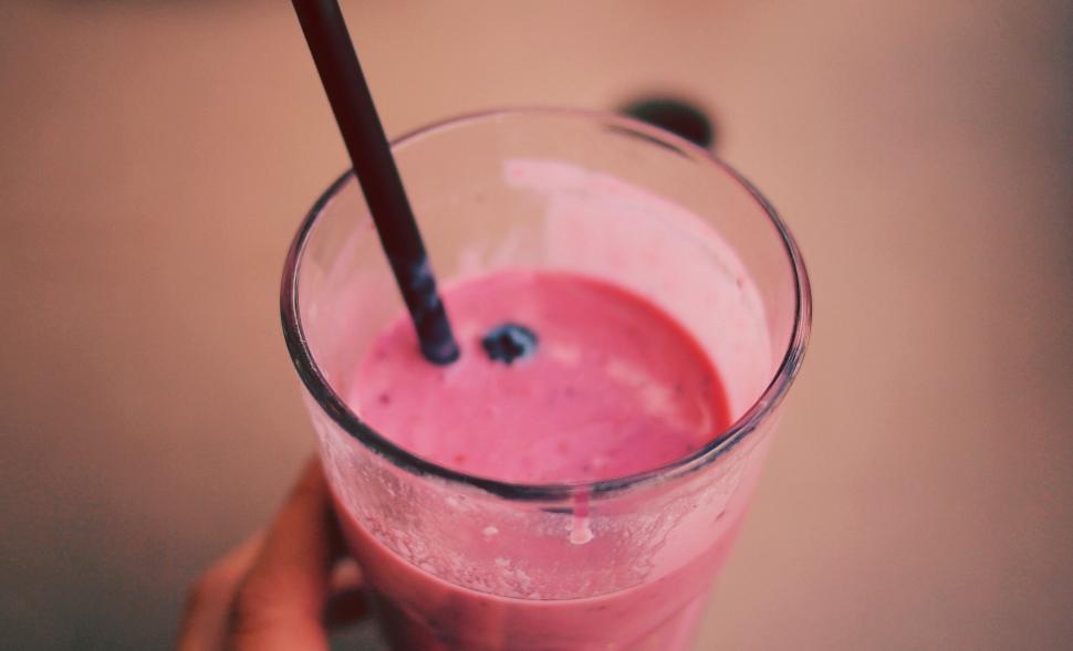 Free Image of Close-up of a fruity pink smoothie with straw 