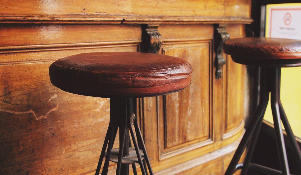 Free Image of Vintage wooden bar stools by an old counter 