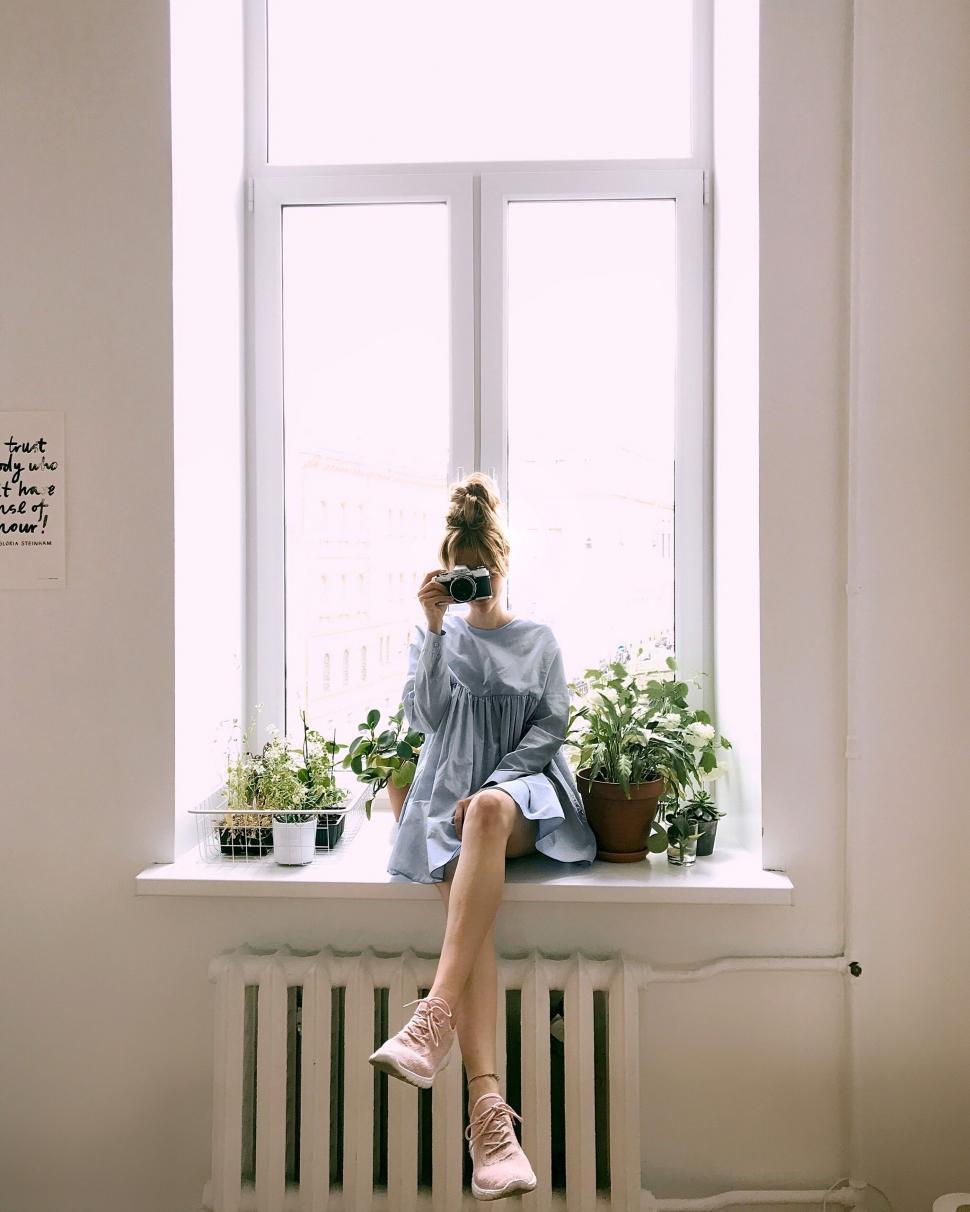 Free Image of Woman sitting by windowsill with plants 