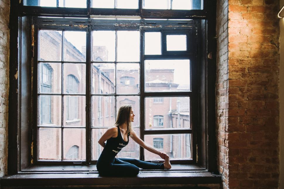 Free Image of Woman in contemplation by a brick window 