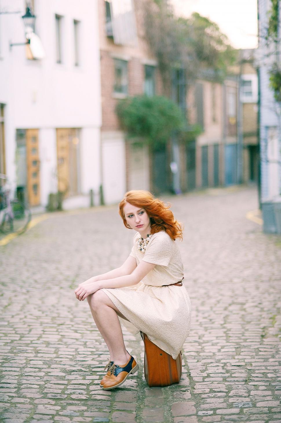 Free Image of Redhead sitting on suitcase in alley 