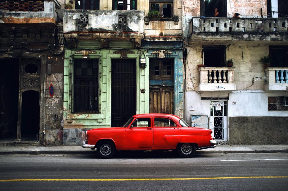Free Image of Classic red car in front of vintage buildings 