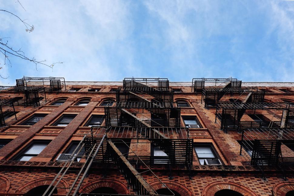Free Image of Looking up at a brick building with fire escapes 