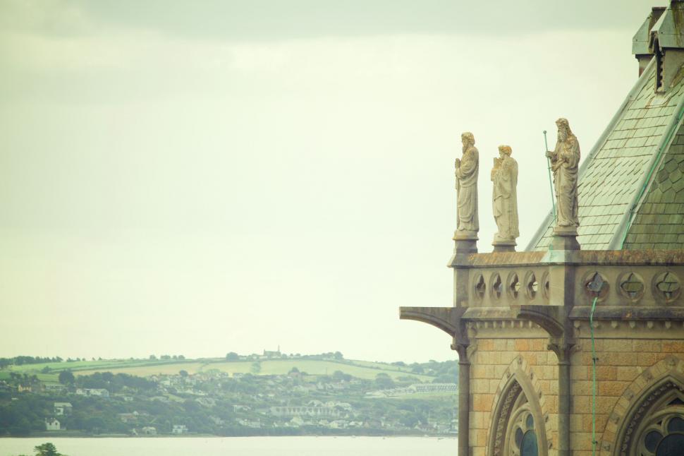Free Image of Statues on a church roof with scenic backdrop 