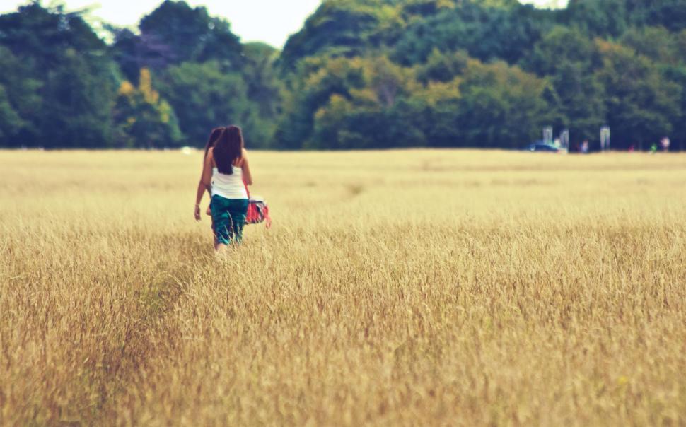 Free Image of Woman walking through golden wheat field 