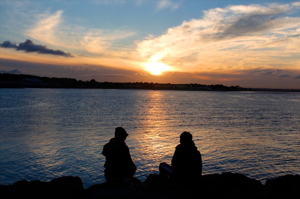 Free Image of Silhouettes sitting by the sea at sunset 