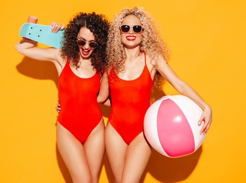 Free Image of Two women in swimsuits holding a ball and a skateboard 