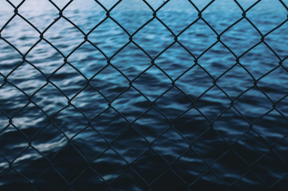 Free Image of Water Body Seen Through Chain Link Fence 