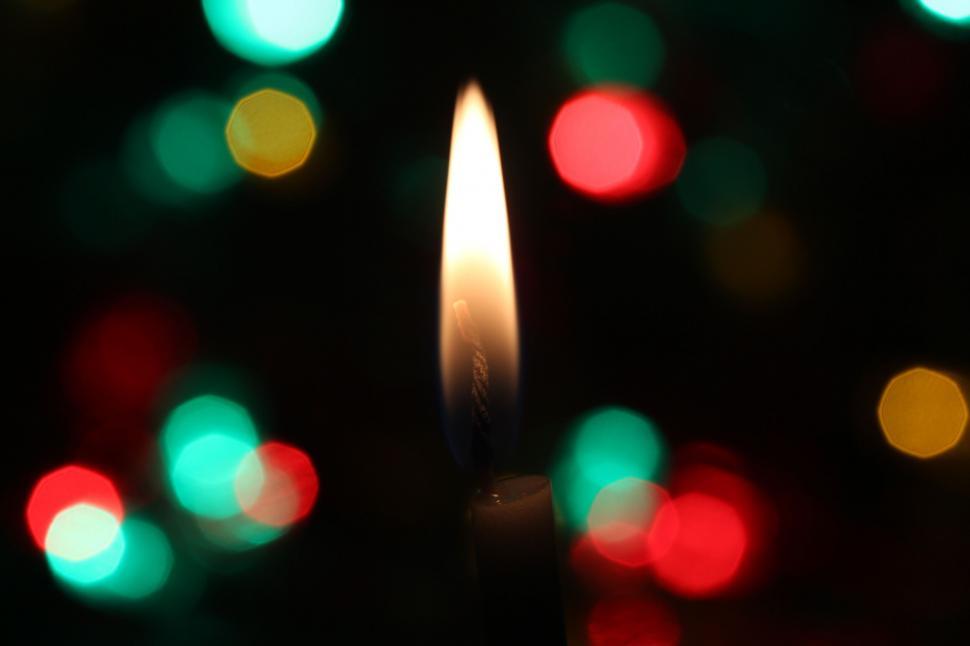 Free Image of Candle flame with colorful bokeh lights 