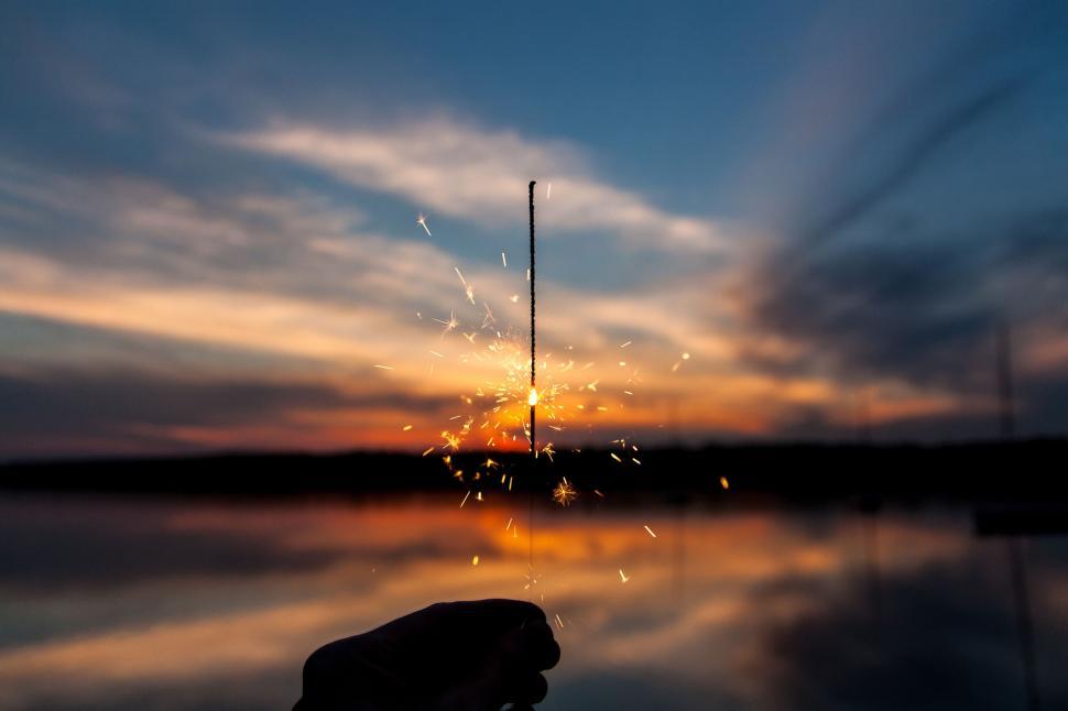 Free Image of Hand holding a single sparkler illuminating the dusk 