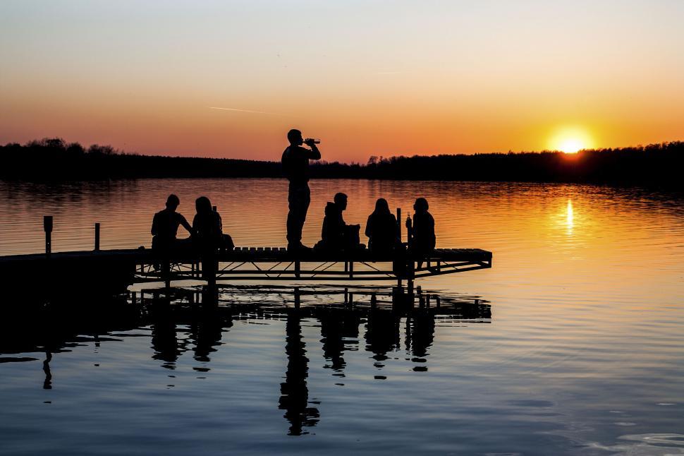 Free Image of Group of friends enjoying a sunset by a lake 